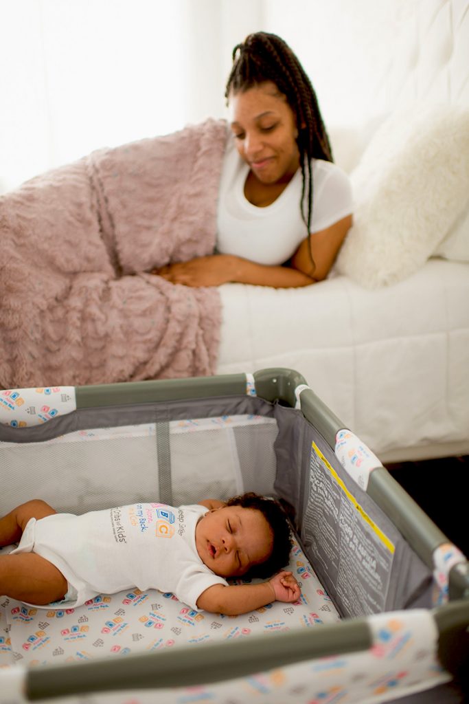 Mother in bed looking at baby sleeping in a safe sleep environment