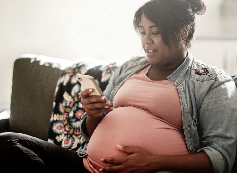 Cropped shot of an attractive young pregnant woman texting while sitting in her living room at home