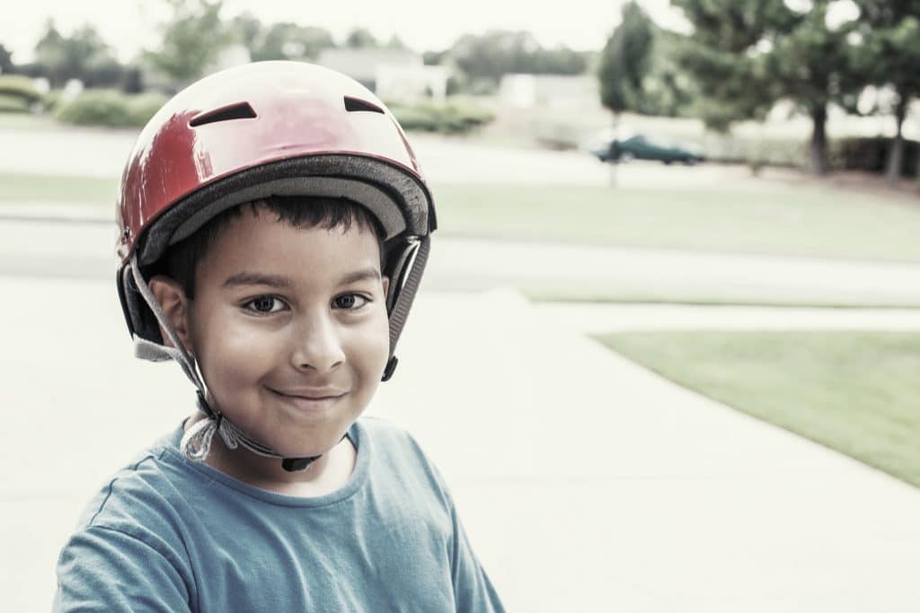 Young boy wearing his helmet while riding his scooter