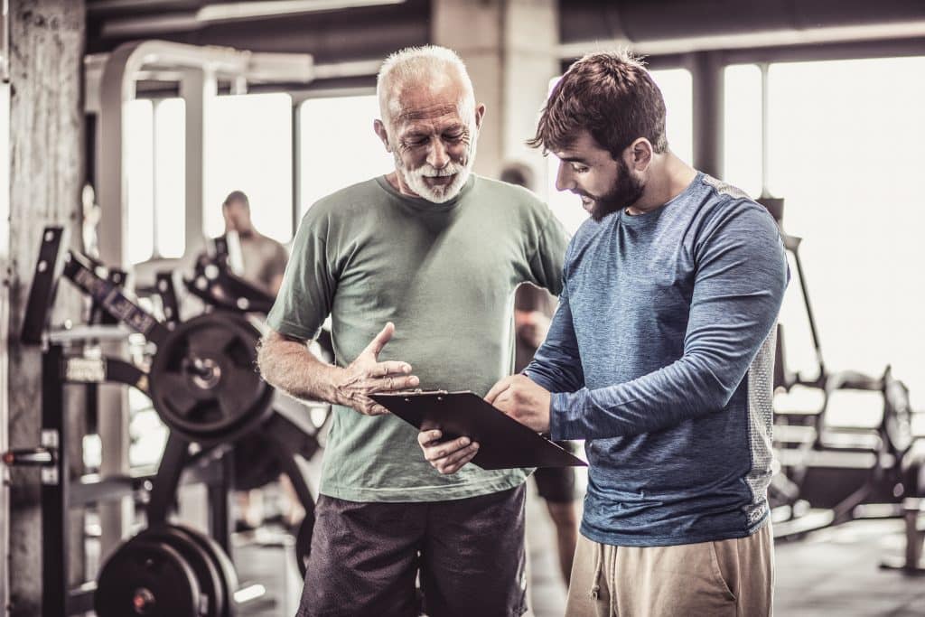Personal trainer giving advice senior man about next exercise.