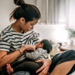 Asian mother breastfeeding baby at home.