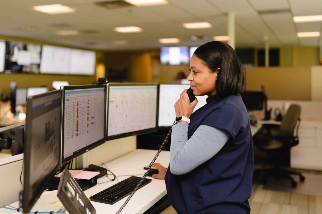 woman taking phone call in front of monitors