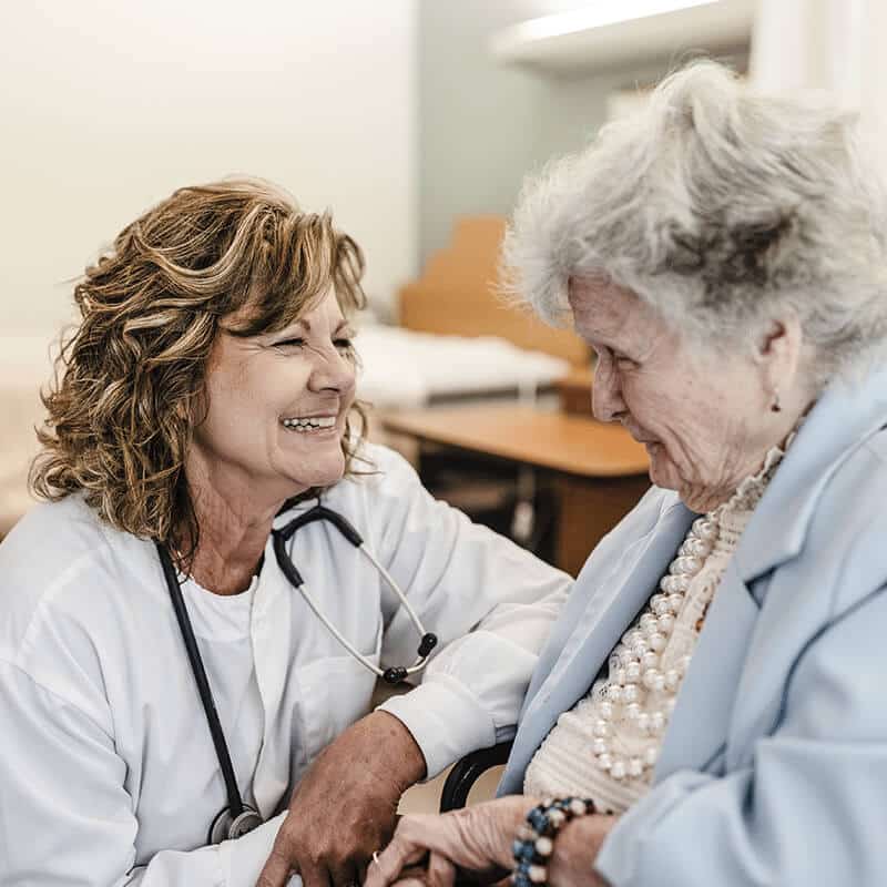 Healthcare professional smiling next to an elderly patient