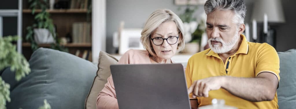 older couple on a couch  studying a laptop screen