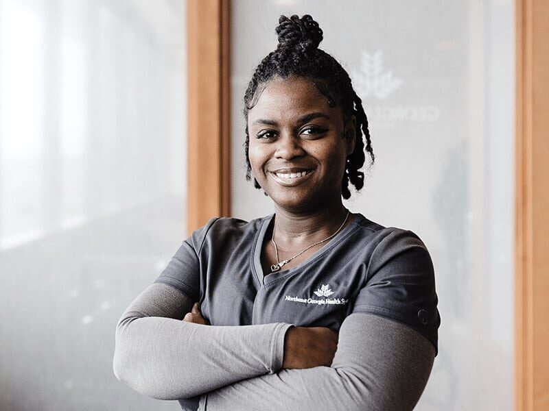 Smiling Registered Nurse standing in hallway.
