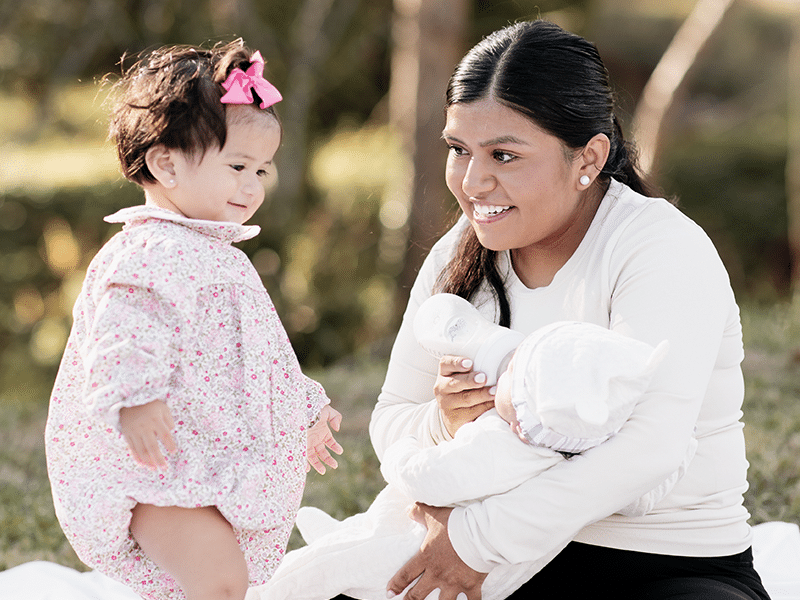 Mother smiling with daughters in park.