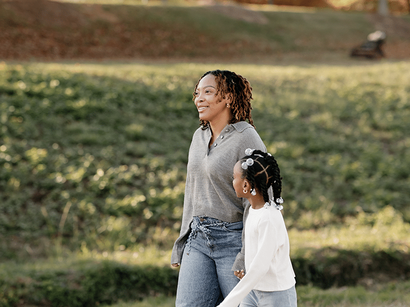 Mother walking with daughter in a park.