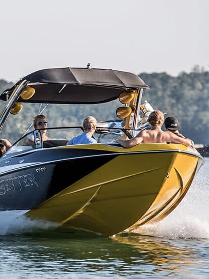 People riding in a yellow and black speedboat on a lake.