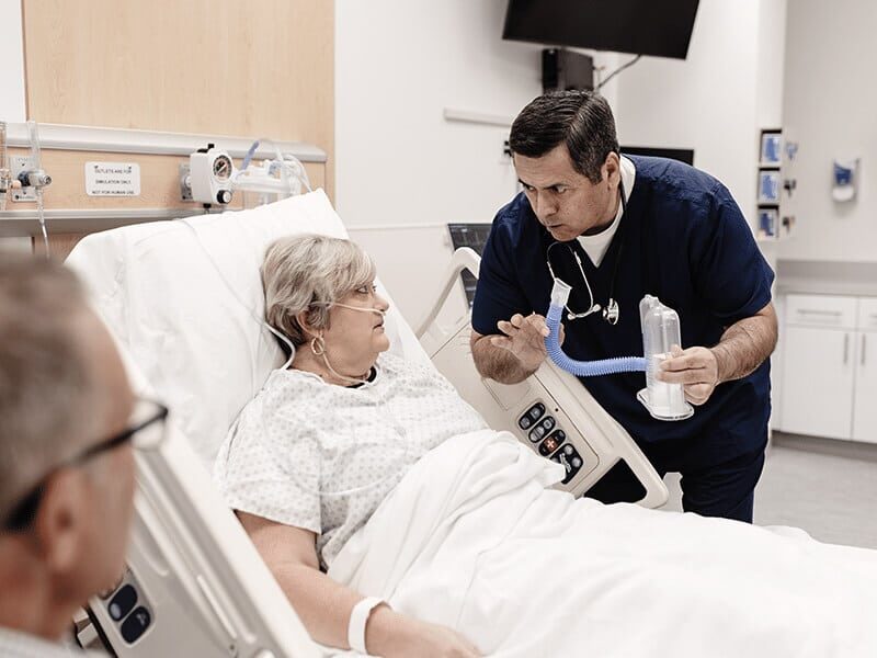 Healthcare employee speaking with a patient in a hospital room