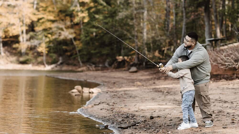 Father fishing with his son by a lake